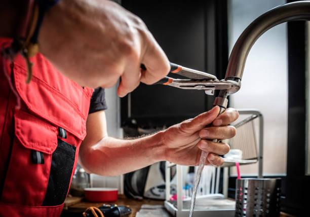 Repairman using adjustable pliers to fix kitchen faucet. Concept of repair.